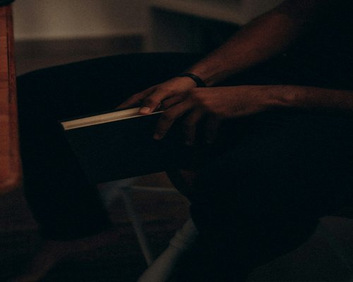 Person holding a book in a relaxed posture during a quiet afternoon