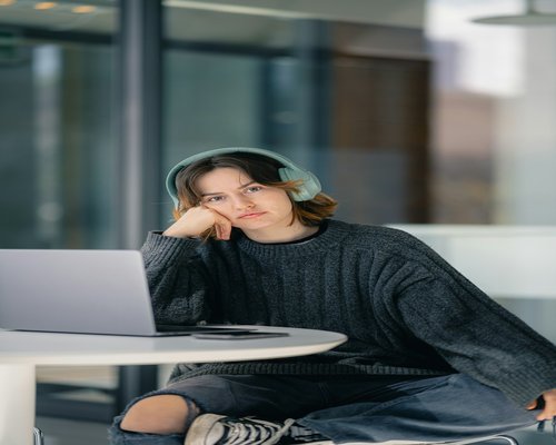 A person looking away from the laptop screen, taking a brief and relaxing pause